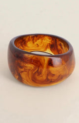 Chunky resin bangle in warm amber and tortoiseshell tones with a glossy marbled finish and organic shape – Volange Paris, Parisian fashion in Sydney (Mosman, Paddington and Bronte) or Australia-wide online.