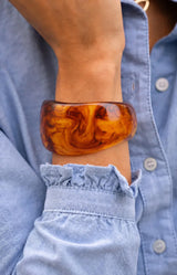 Chunky resin bangle in warm amber and tortoiseshell tones with a glossy marbled finish and organic shape – Volange Paris, Parisian fashion in Sydney (Mosman, Paddington and Bronte) or Australia-wide online.